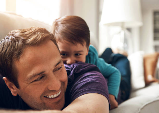 istock Playing, happy and father with child on sofa for bonding, laughing and relax together on weekend. Family, morning and dad with young boy on couch for playful relationship, love and fun in living room 2159042427
