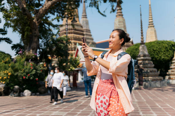 istock Smiling asian woman taking a photo with cell phone while exploring the ancient architecture 2159050223
