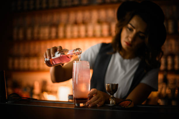 istock Female bartender is preparing a cocktail, pouring a pink drink 2159060572