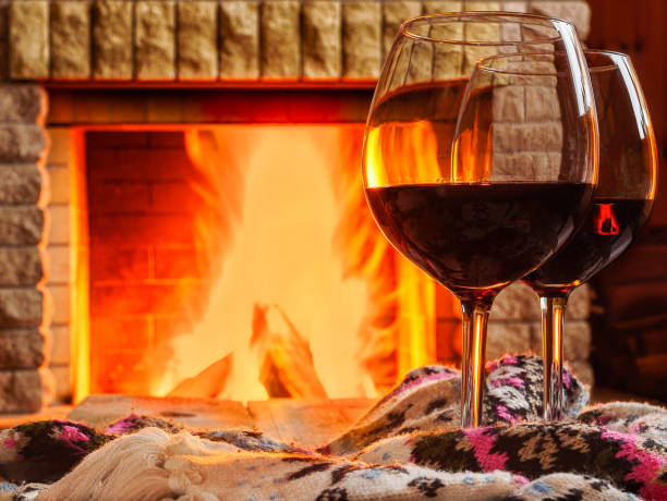 istock Glasses of red wine before cozy fireplace. 2159066268