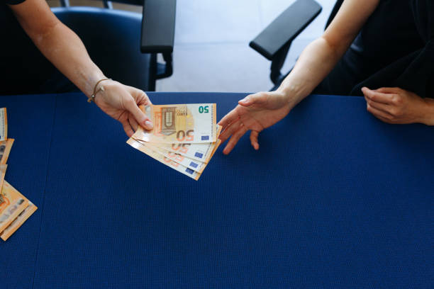 upper view of two women hands giving to each other and accepting the money over the blue table