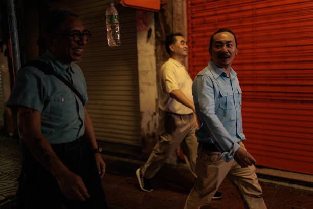 Male friends walking on the street at night in Bangkok, Thailand.