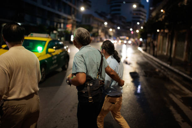 Male friends crossing the street at night in Bangkok, Thailand.