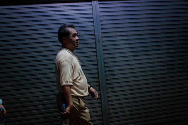 Mature Thai man walking on the street at night in Bangkok, Thailand.