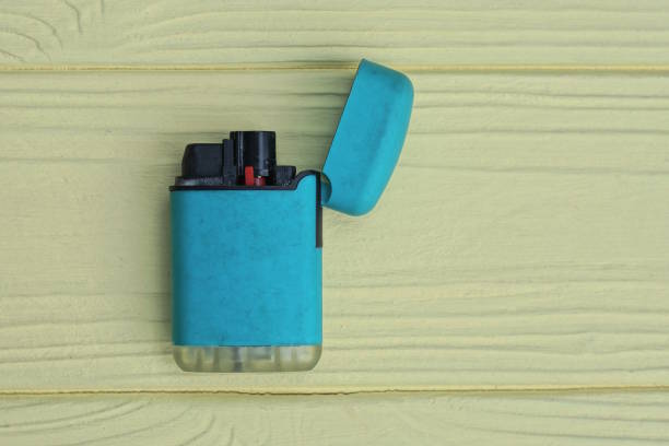 istock blue open lighter lies on a yellow wooden table 2159073316