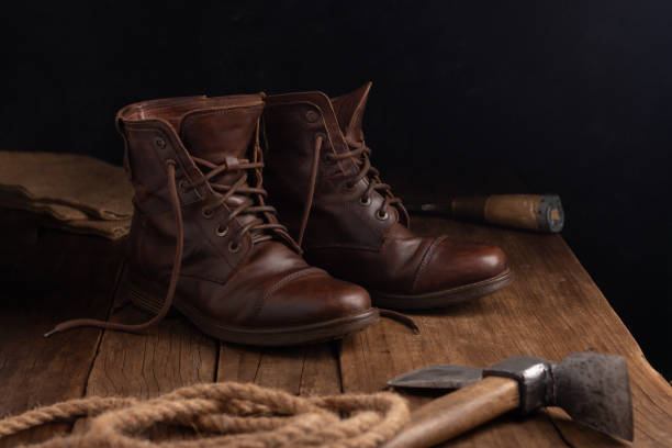 Boots on a wooden table next to an axe and a rope