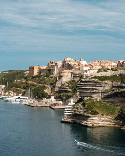 Bonifacio, Corsica, France - 27th May 2024: A small dinghy passes the walled citadel of Bonifacio in Corsica as it enters the harbour