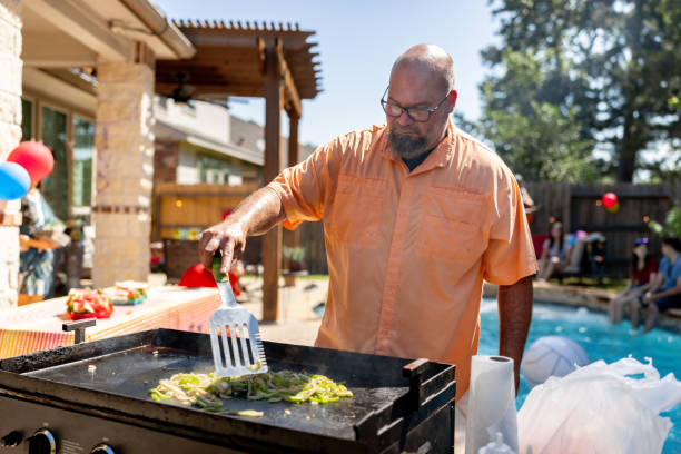 istock Man making food on the barbecue while having a pool party 2159102819