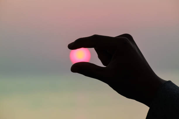 istock Silhouette of fingers holding sunrise 2159103353