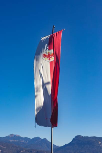 istock A vertical flag with a red and white design featuring an eagle emblem against a clear blue sky 2159111998