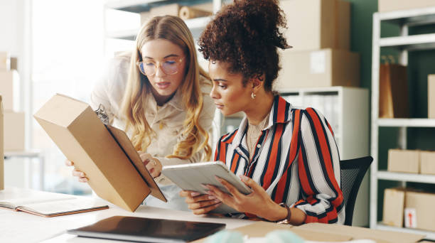 istock Women, tablet and teamwork with logistics, package and e commerce checklist for online shop, stock or supply chain. Small business people or seller with digital tech, box and clipboard for web order 2159117390