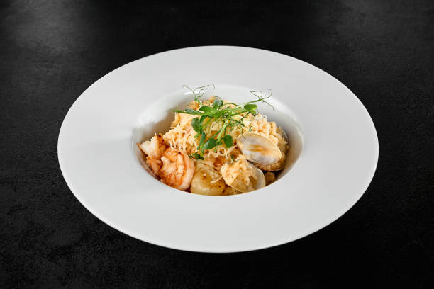 Seafood Risotto with Scallops and Shrimp in a White Plate on Black Background