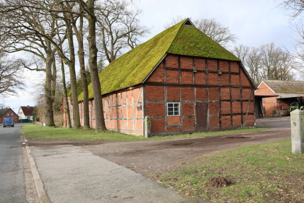 A mosscovered brick barn in a rural setting exudes a classic, rustic, and peaceful ambiance