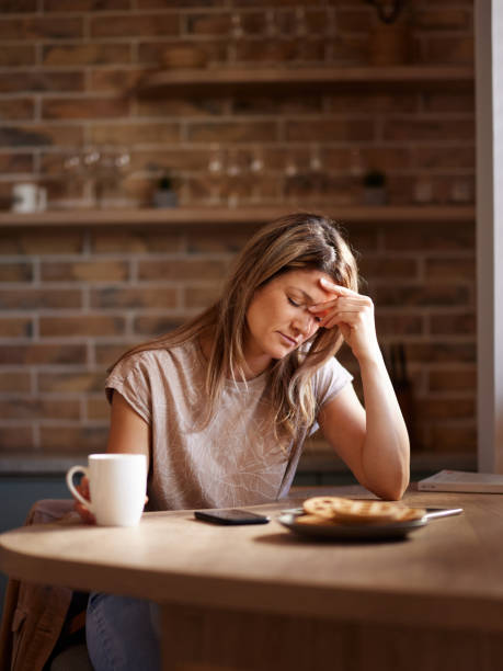 istock Woman holding her head in pain at dining table. 2159124217
