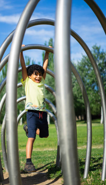 istock 8 year old Latino boy playing in a park hanging from a structure 2159126009