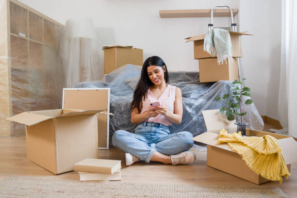 istock woman using smartphone while sitting on floor in new apartment 2159126095