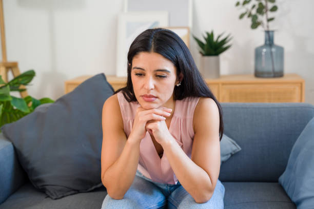 istock Sad woman is sitting on sofa at home 2159126230