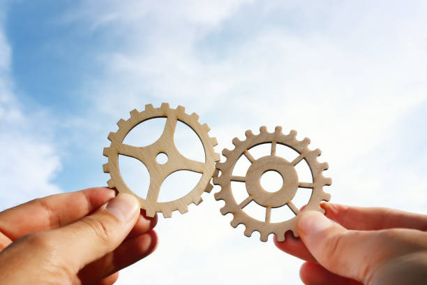 istock Hand spinning gears in front of sky 2159126615