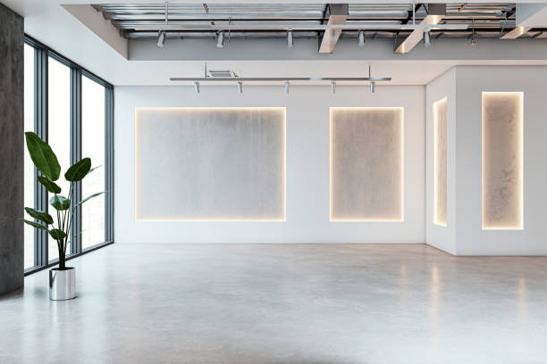 istock Modern gallery interior with illuminated frames, concrete floor, large windows, and a plant. Concept of a minimalist art exhibition space. 3D Rendering 2159126932