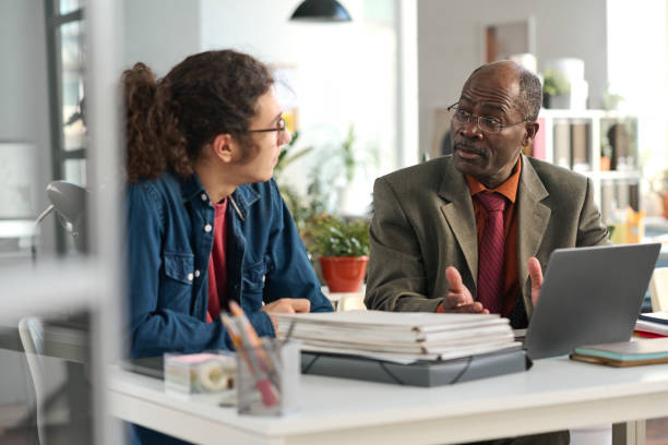 istock Senior Black Man with Young Colleague Discussing Project 2159129433