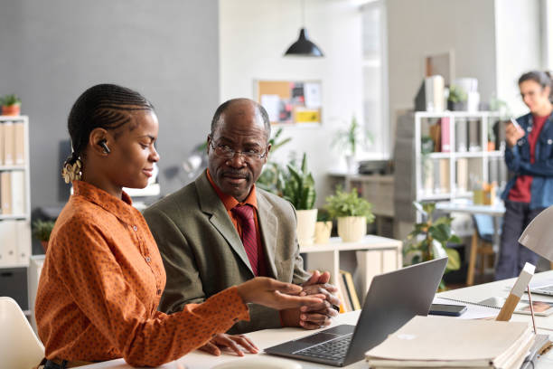 istock Young Woman Instructing Senior Colleague at Office 2159129519