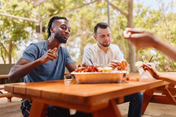 istock Three friends sitting and eating seafood during the day 2159130382