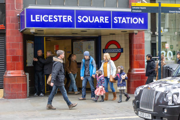 People entering and leaving the Leicester Square London underground station street entrance. A young family of four are pictured.