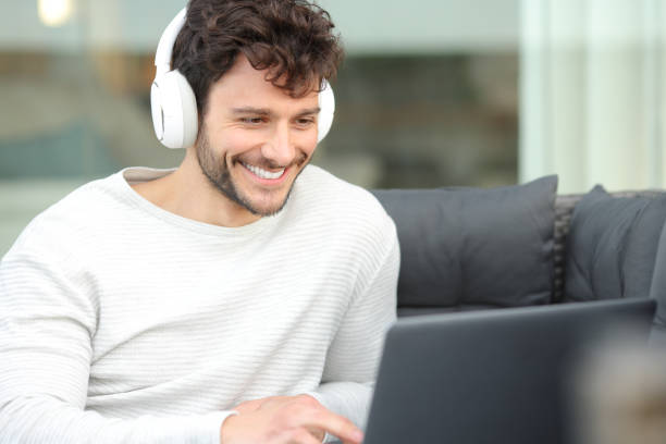 istock Happy man with headphone watching media on laptop 2159132165