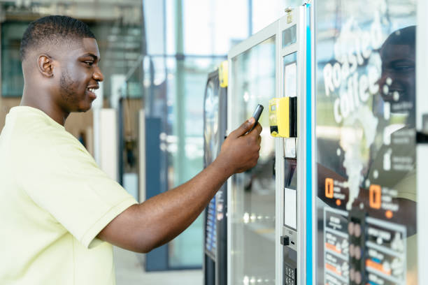 istock Paying with mobile phone. Young traveler black man choosing a snack or drink at vending machine 2159132190