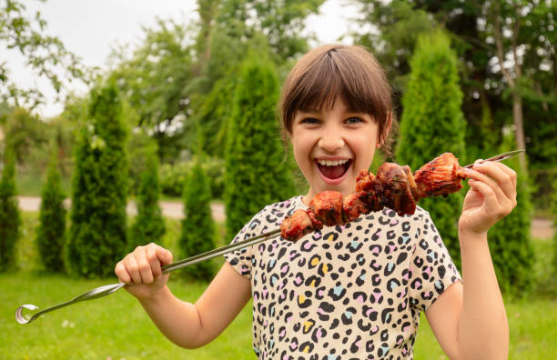 Little girl with pleasure eats shish kebab.