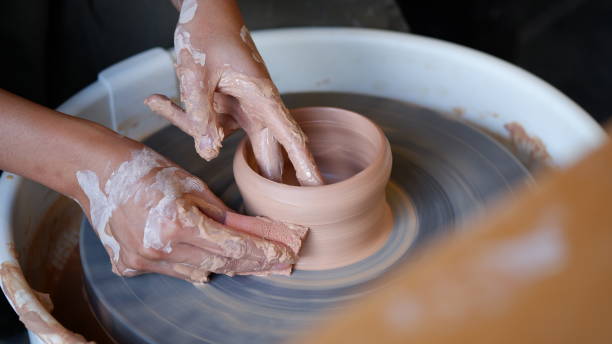 istock Hand smoothing clay pottery with a foam at throwing wheel. 2159132430