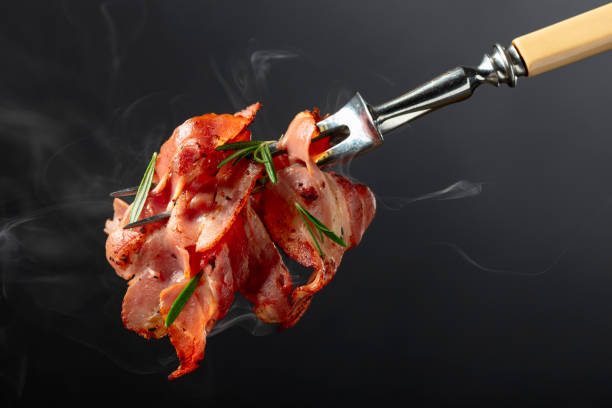 istock Hot fried bacon slices with rosemary on a fork. 2159133194
