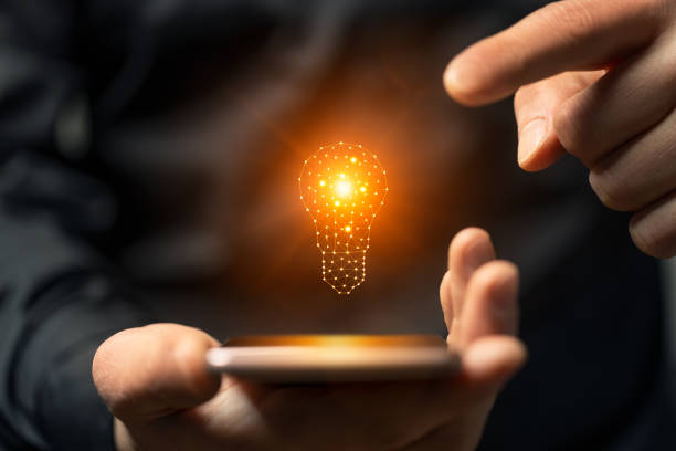istock Idea concept with hand holding smartphone with glowing light bulb. 2159138018