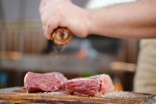 istock Unrecognizable man seasoning raw beef steak with pepper 2159138455