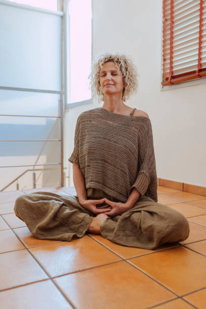 Middle aged woman practicing yoga and meditating in lotus position