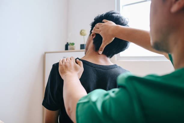 Home Healthcare Physiotherapist Doing Neck Theraphy To Patient At Home chiropractor stock pictures, royalty-free photos & images