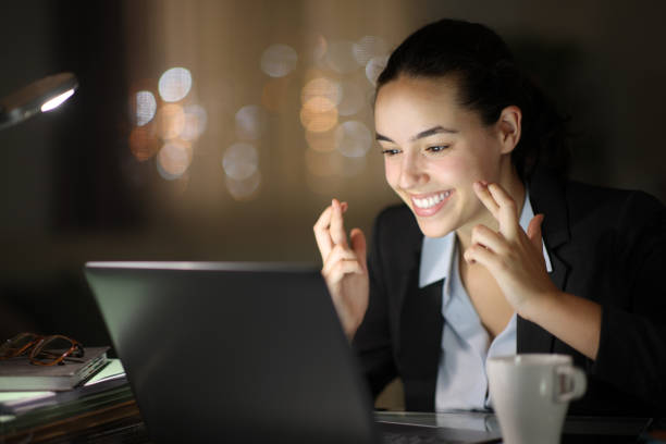 istock Happy executive working in the night crossing fingers 2159144167