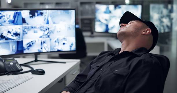 istock Security guard, computer screen and tired by cctv monitor for protection, data center or building safety. Inspection, video surveillance agency and control room with footage, technology and sleeping 2159144998