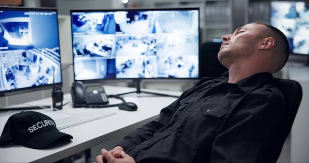 istock Security guard, computer screen and tired by cctv monitor for protection, data center or building safety. Inspection, control room with footage and video surveillance agency, tech and sleeping man 2159144999