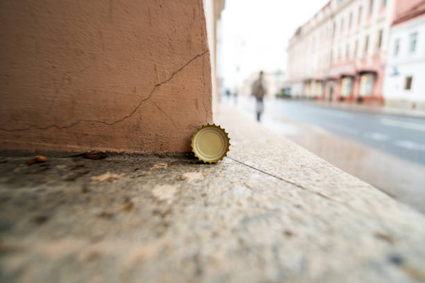 soda bottle cap resting on its side near a concrete wall, a simple yet evocative urban still life
