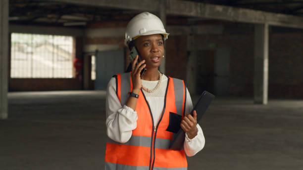 istock Female Architect Discussing Construction Plans on Phone at Construction Site 2159149476