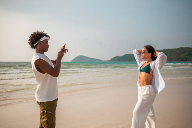 istock Black Male Photographing Hispanic Girlfriend at Beach 2159151492