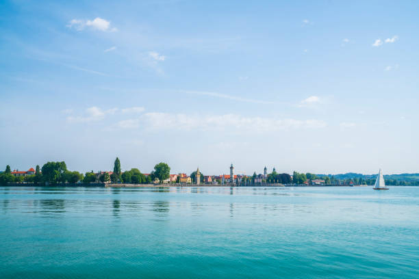 Germany, Lindau island harbor lighthouse view from waterside nature landscape reflecting in silent bodensee lake water early in the morning