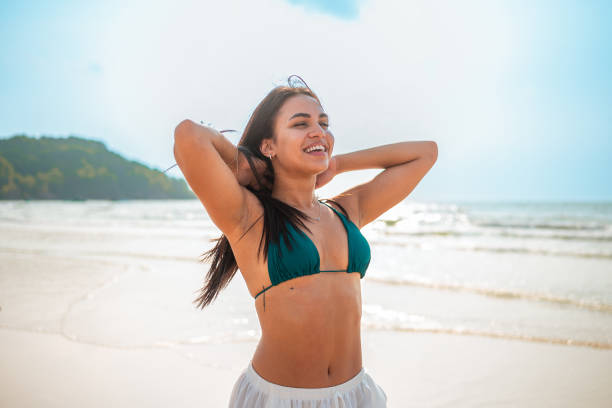 Beautiful girl dressed in bikini wearing a hat with a beach towel wrapped around her waist in Caraíva beach, Bahia, Northeastern Brazil. DSLR Canon Mark IV.
