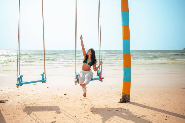 istock Joyful Hispanic Woman Enjoying Swing on Sunny Beach 2159160356