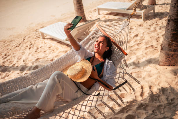 istock Smiling Hispanic Woman Enjoying Beach Vacation and Taking Selfie 2159165096