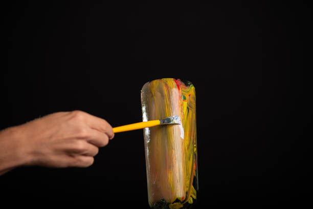 istock A glass bottle being painted with a yellow brush. 2159167487
