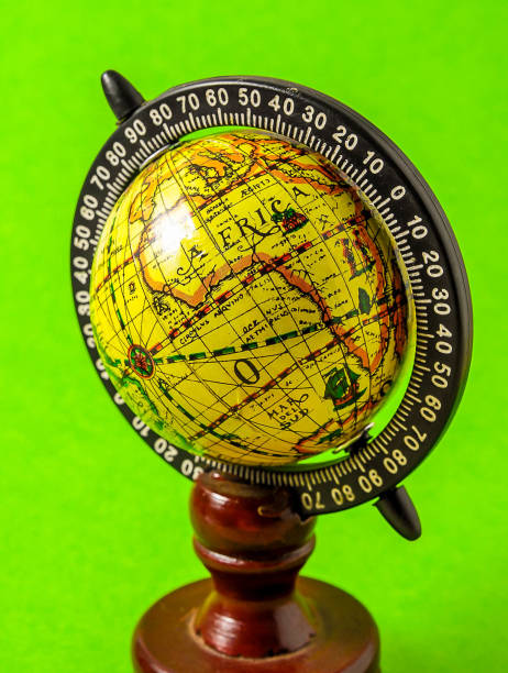 A globe sits on top of a stack of books. The globe is yellow and has a brown base. The books are stacked on top of each other, with the bottom book being the largest