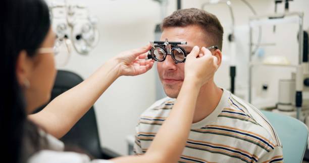 istock Optometrist, patient and assessment in clinic for eye exam, optometry and vision with phoropter. Specialist, man and testing machine in hospital for healthcare, wellness or ophthalmology for glaucoma 2159175380