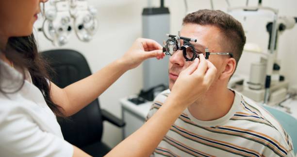 istock Optometrist, patient and assessment in clinic for eye exam, optometry and vision with phoropter. Specialist, man and testing machine in hospital for wellness, healthcare or ophthalmology for glaucoma 2159175389